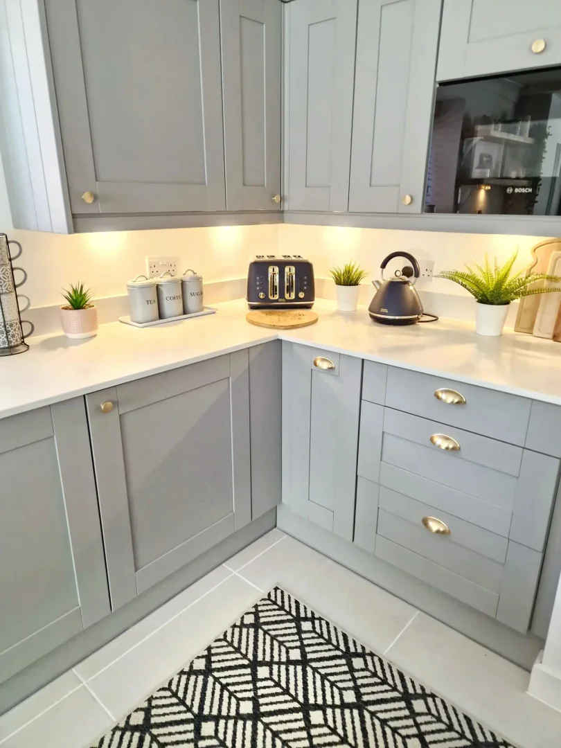 7. Compact Corner Layout with Bold Brass Touches (Light Gray Kitchen Ideas)